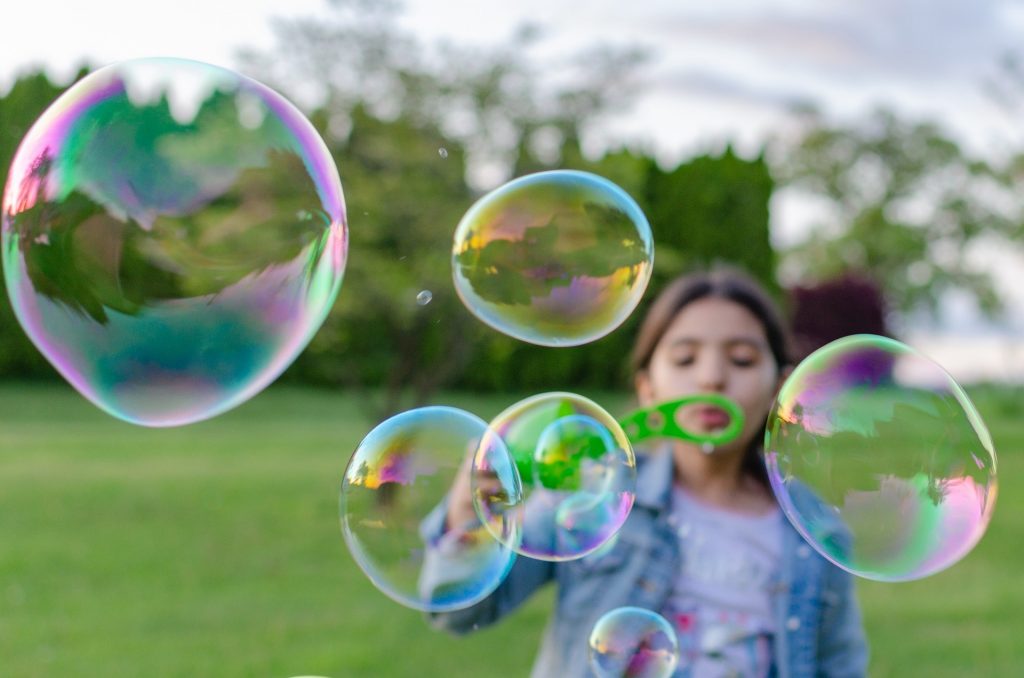 girl blowing bubbles outside